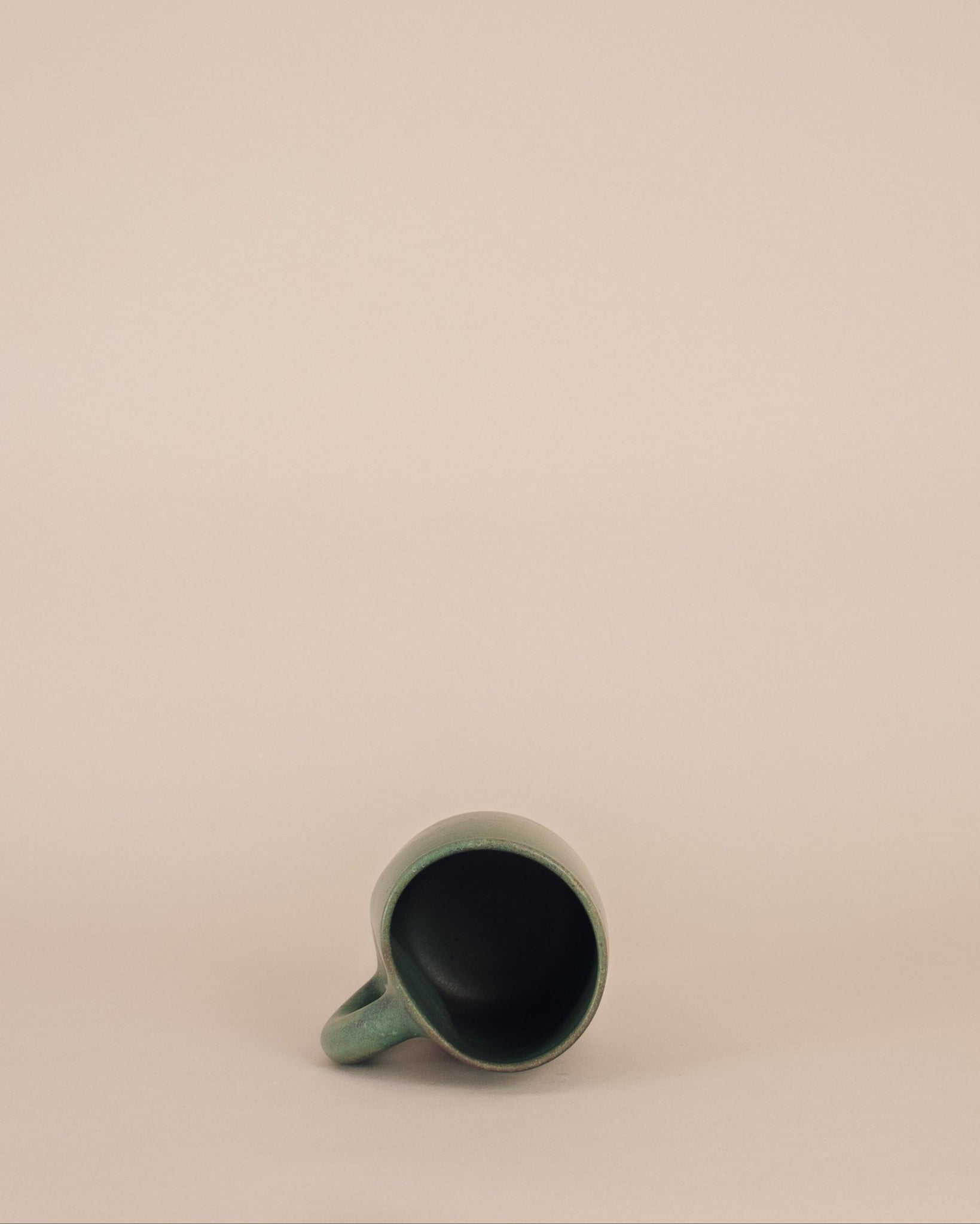 Green ceramic mug on a beige background
