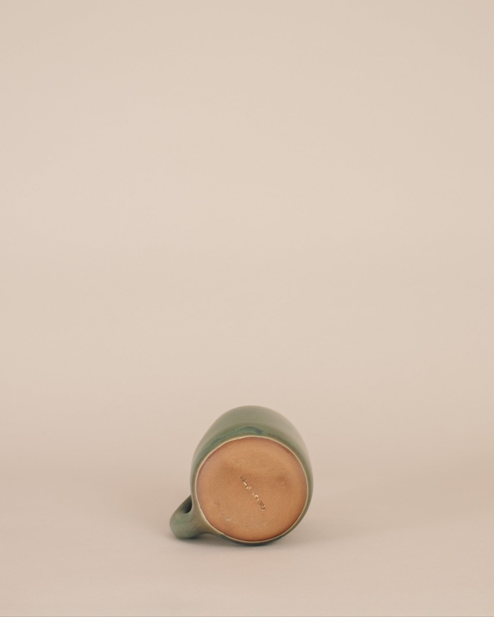 Green ceramic mug on a beige background