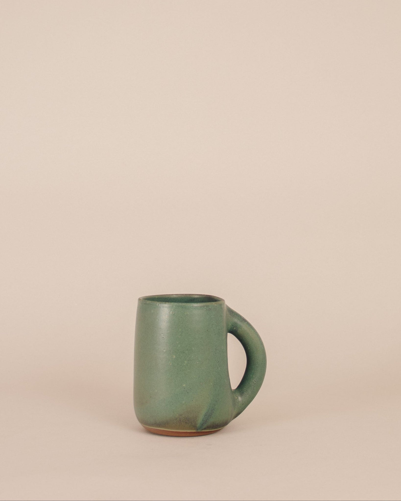 Green ceramic mug on a beige background